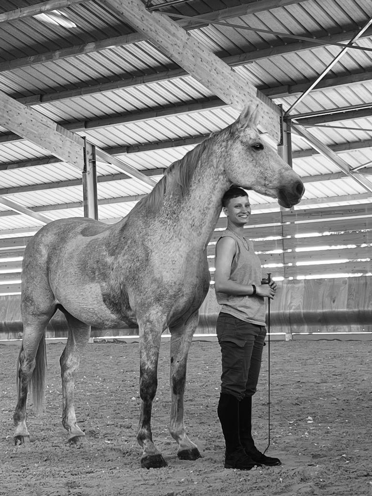 Zelda aux côtés de son cheval blanc, en noir et blanc